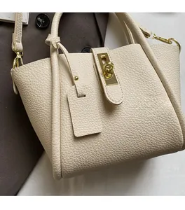 Close-up of cream pebble leather handbag featuring a golden turn-lock and soft texture