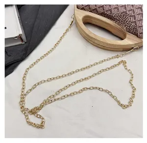 Detail of wooden handle and gold chain strap on the textured straw woven handbag