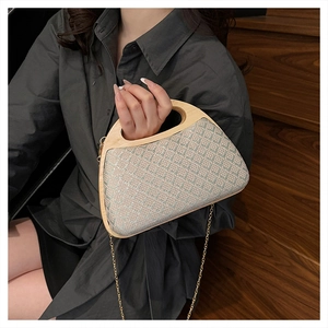 Detail of hand-woven straw bag with smooth light wood handle and gold chain strap