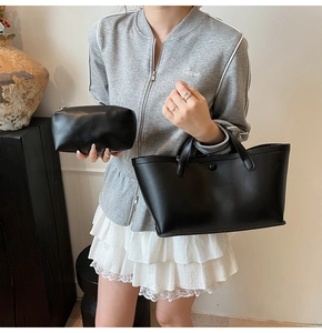 Detail view of the black minimalist tote and zipper pouch set worn by a model