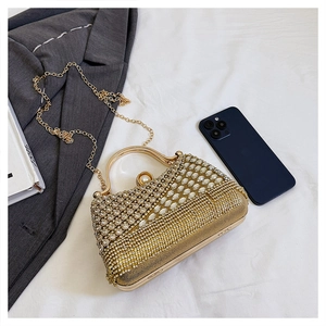 Macro detail of gold evening clutch with rhinestones, metal handle, and pearl clasp