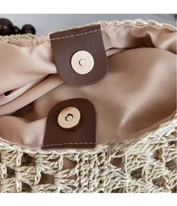 Detail of magnetic buckle closure and pink satin lining on straw woven beach bag