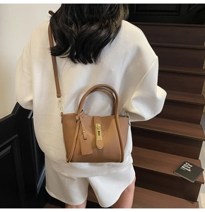Close-up of brown textured leather handbag featuring polished gold hardware and double handles