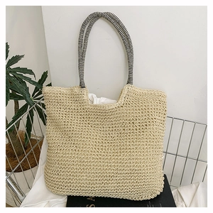 Macro shot of hand-woven beige tote bag with black and white striped textile handles