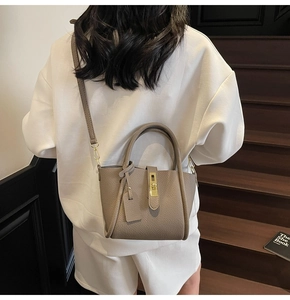 Detailed shot of taupe pebbled leather handbag with gold twist lock and dual top handles
