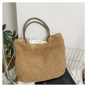 Close-up of handwoven straw tote featuring stylish black and white striped handles
