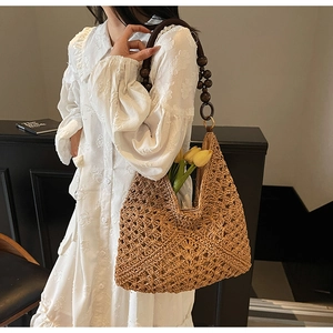 Detail of hollow woven straw bag with dark brown wooden bead handle and tulip decoration