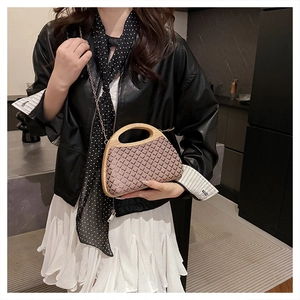 Detail of hand-woven checkered straw bag with curved wooden handle and gold chain strap