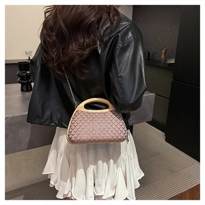 Detail of hand-woven geometric straw handbag with elegant wooden handle and metal chain