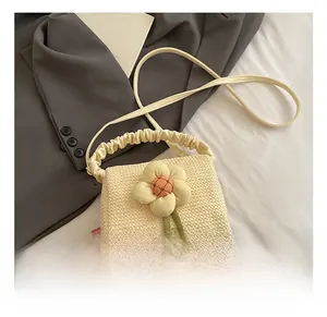 Detail of beige woven beach bag with floral applique and pleated handle on a grey blazer