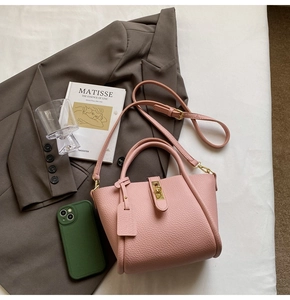 Detailed view of pink lychee pattern handbag with metal twist lock and dual handles