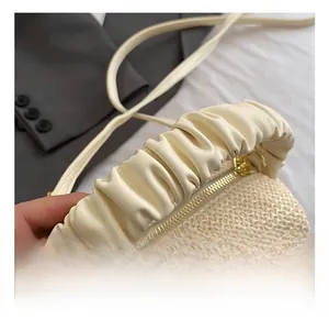 Detail of cream straw handbag showing ruched leather handle and fine woven texture