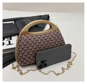 Detail of woven geometric pattern handbag with wooden handle and gold chain strap