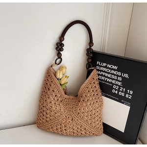 Detail showing hollow-out knit texture and wooden bead handle of this straw handbag