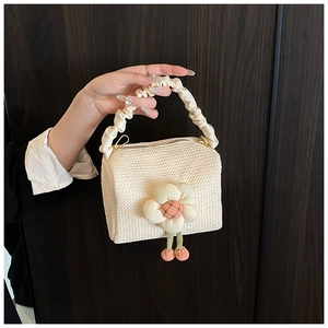 Detail of cream straw bag with floral accents and a unique ruffled scrunchie handle