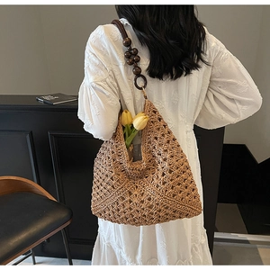 Detail of straw woven bag featuring dark wooden bead strap and interior tulip decoration