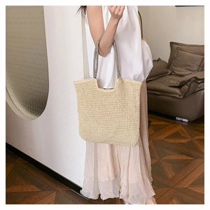Detail of hand-woven tote bag with striped handles and natural texture on model