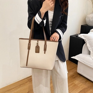 Minimalist beige tote bag with brown handles shown in a modern interior setting