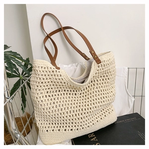 Detail showing hollow woven texture of off-white tote bag with brown leather straps