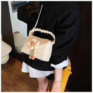 Detail of straw woven handbag with fabric flower charm and creamy ruched handle