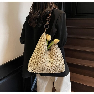 Detail of hollow-out straw handbag with beaded wooden handle and crochet floral texture