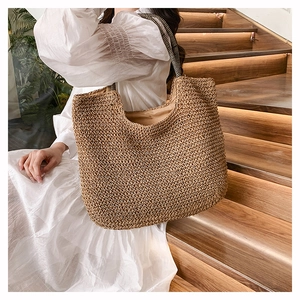 Detail of handcrafted brown woven straw tote bag with black and white striped strap