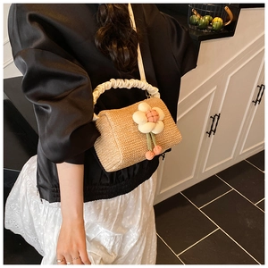 Detail of straw woven bag with floral ornament and ruched satin handle in beige