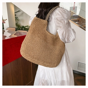 Detail of hand-woven straw tote bag with striped handle texture and spacious interior design