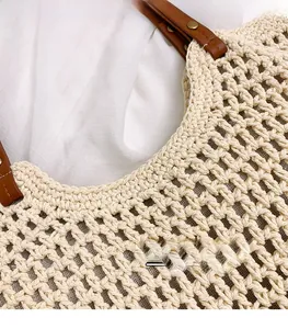 Detailed close-up of beige woven texture with brown leather handle and gold metal rivets