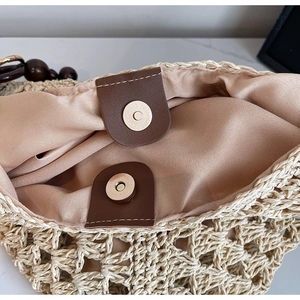 Detail of straw woven bag with magnetic buckle closure and beige fabric lining