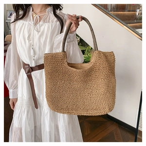 Detail of hand-woven khaki tote bag featuring contrasting black and white striped handles