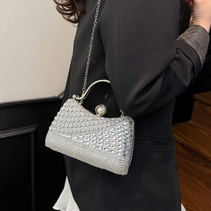 Elegant silver rhinestone evening bag with pearl clasp and chain strap on a black blazer
