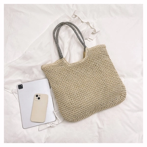Detail shot of a beige woven tote bag with striped handles and tablet for size scale