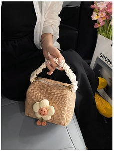 Detail of straw woven handbag with 3D flower accent and white ruched cloud handle