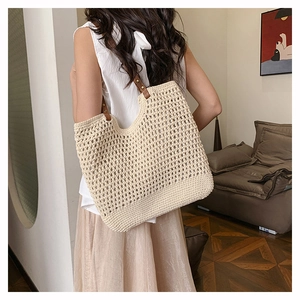 Detailed view of beige hollow crochet tote bag with brown leather handle on shoulder
