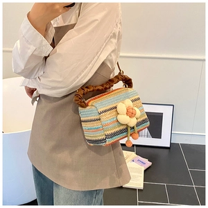 Detail of colorful striped straw handbag with 3D plush flower and brown leather handle