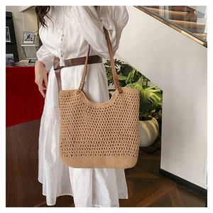 Detail of hollow woven tote bag with brown leather straps and vintage metal rivets