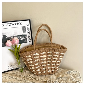 Detail of handwoven straw tote bag with geometric pattern and round handles in a home setting