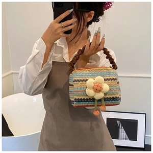 Detail of colorful striped straw bag with a large floral 3D appliqué and pleated handle
