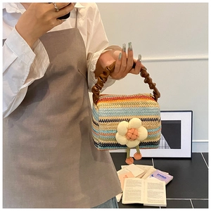 Detail of rainbow straw tote bag featuring brown pleated handles and 3D floral charm