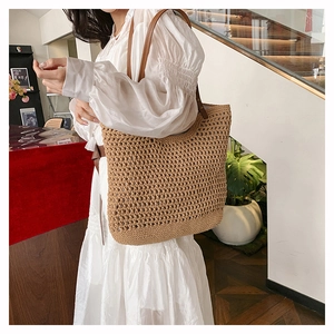 Detailed side view of a hollow-out woven straw tote bag with brown leather handles