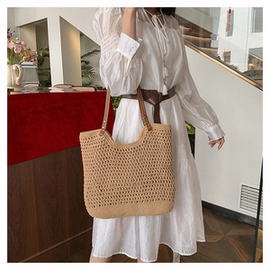 Close-up of large woven tote bag with hollow crochet pattern and brown leather straps