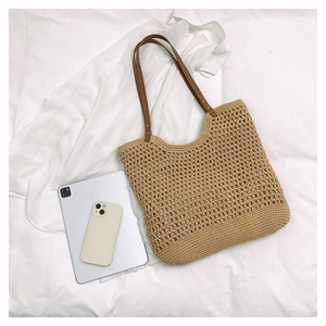 Top view of hollow woven straw bag with dark brown leather straps and detailed texture