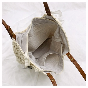 Detail view of woven handbag with brown leather strap and inner zipper compartment