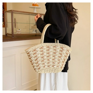 Detail of a wave-patterned woven straw tote bag with round handles in a casual setting