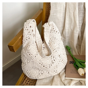 Detail of cream crochet woven bag with floral hollow patterns on a rustic wooden chair