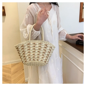 Close-up of handmade straw tote bag featuring contrast weave pattern and sturdy dual handles