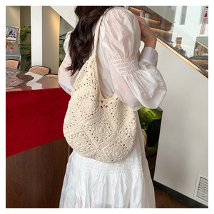 Detail of beige hand-knitted crochet hobo bag showing intricate openwork woven patterns