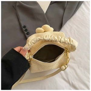 Detail of cream woven handbag showing pleated cloud handle, zipper, and adjustable strap