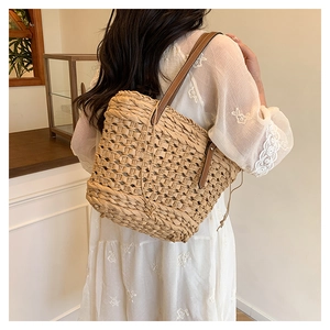 Détail du sac seau en paille tressée montrant la texture fine et la bandoulière en cuir